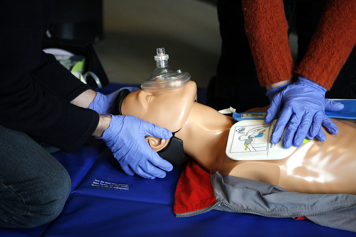 Close up of CPR training with two trainees with blue gloves.