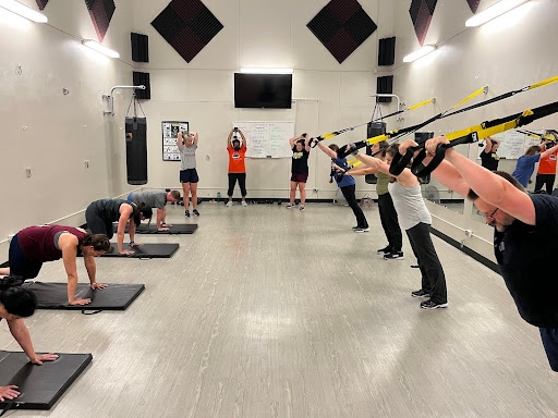 Group class working our on mats and TRX system