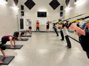 Group class working our on mats and TRX system