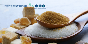 spoonful of brown sugar on top of a pile of white sugar with sugar cubes