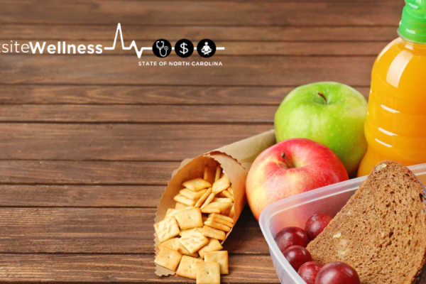Grapes and Sandwhich in a plastic container with an orange drink and apples
