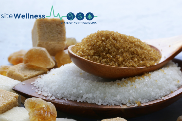 spoonful of brown sugar on top of a pile of white sugar with sugar cubes
