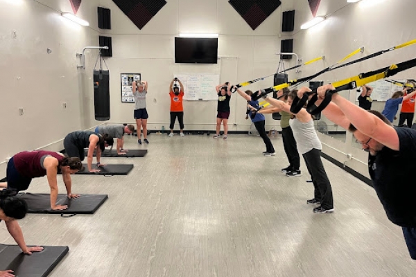 Group class working our on mats and TRX system